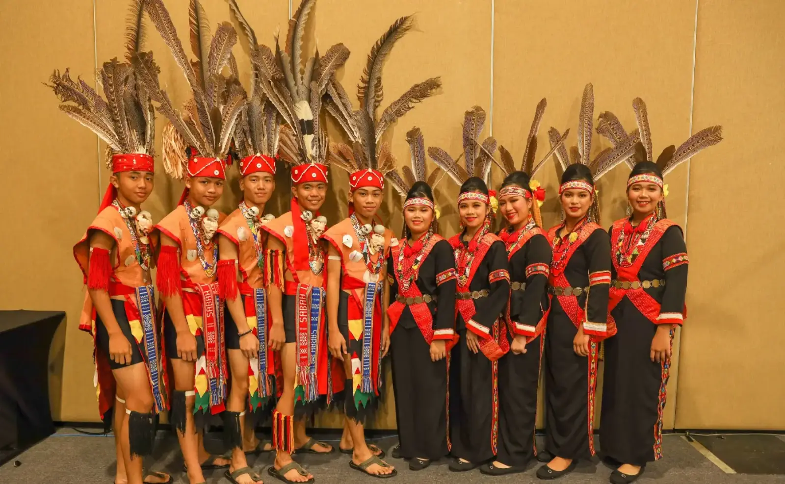 Young performers in traditional Sabahan attire with feathered headdresses